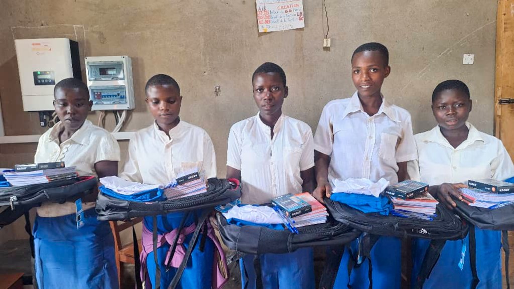 Five students standing indoors, each holding backpacks filled with notebooks and school supplies.